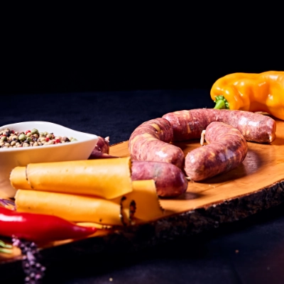 Metzgerei Thumm Filderstadt-Frisches Fleisch und andere regionale Produkte-Grid-_4 Hausgemachte grobe Bratwurst mit Cheddarfüllung, angerichtet mit Paprika, Chili und Gewürzen auf Holzbrett