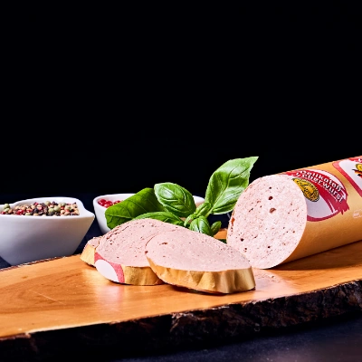 Hausgemachte Leberwurst – feinwürzige Leberwurst in Scheiben geschnitten, dekoriert mit Basilikum auf Holzbrett