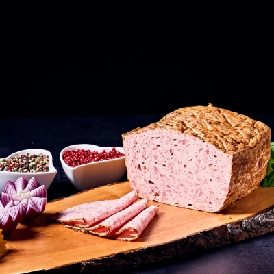 Hausgemachter Fleischkäse – frisch gebacken, aufgeschnitten und serviert auf rustikalem Holzbrett mit Zwiebeldeko
